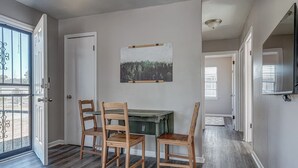 Un comedor con una mesa y cuatro sillas, un cuadro en la pared y una puerta que da al exterior.