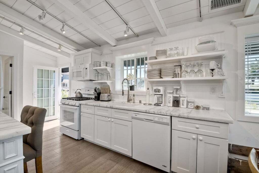 A modern kitchen with white cabinetry, a marble countertop, and various kitchen appliances.