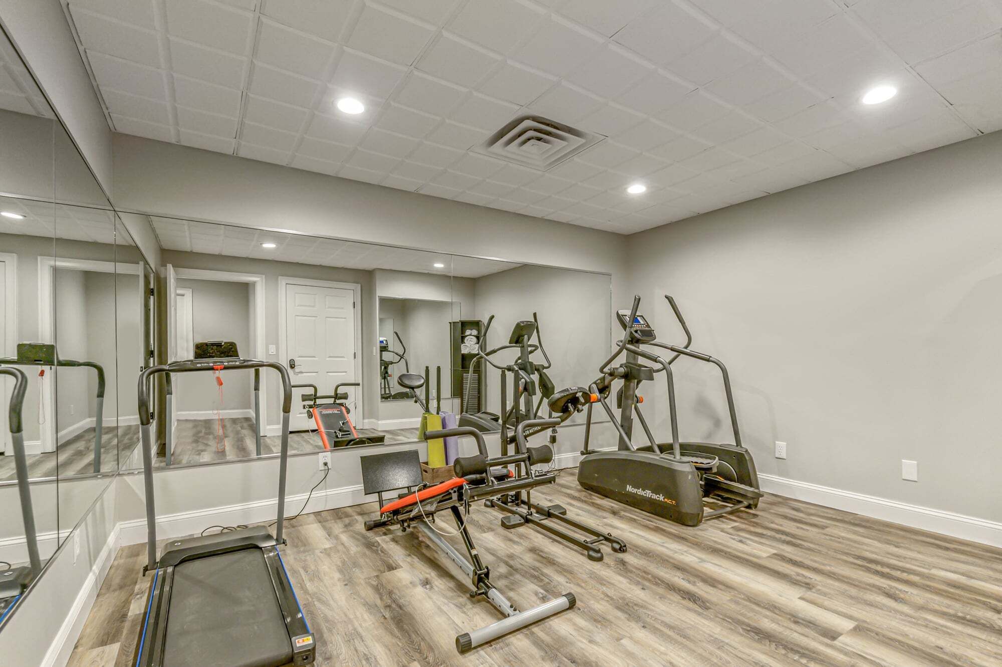A gym with treadmills, elliptical machines, and a NordicTrack.