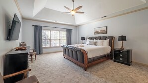 A bedroom with a large bed, a ceiling fan, a desk, a chair, a TV, and a window with curtains. - 530 Waterford Drive, Cartersville (Cartersville)