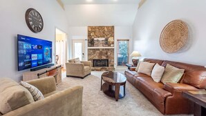 A living room with a stone fireplace, leather sofa, and a flat-screen TV. - 530 Waterford Drive, Cartersville (Cartersville)