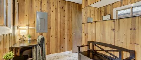 A modern bathroom with wooden paneling, a black vanity, a mirror, and a small table with a lamp and plant.