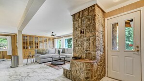 A spacious living room with a stone accent wall, a built-in fireplace, and a large window offering a view of the outdoors. - 4925 Pike Unit1 (Cascade)