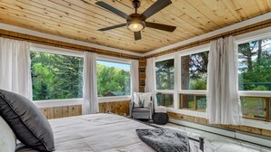 A bedroom with a bed, a ceiling fan, and large windows with curtains. - 4925 Pike Unit1 (Cascade)