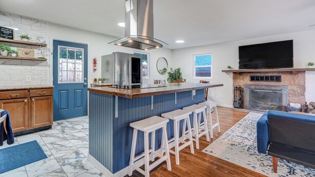 Una cocina moderna con una isla central, una chimenea de piedra y un televisor montado encima.