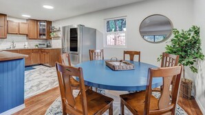 Una cocina con armarios de madera, horno empotrado y comedor con una mesa azul y sillas de madera.
