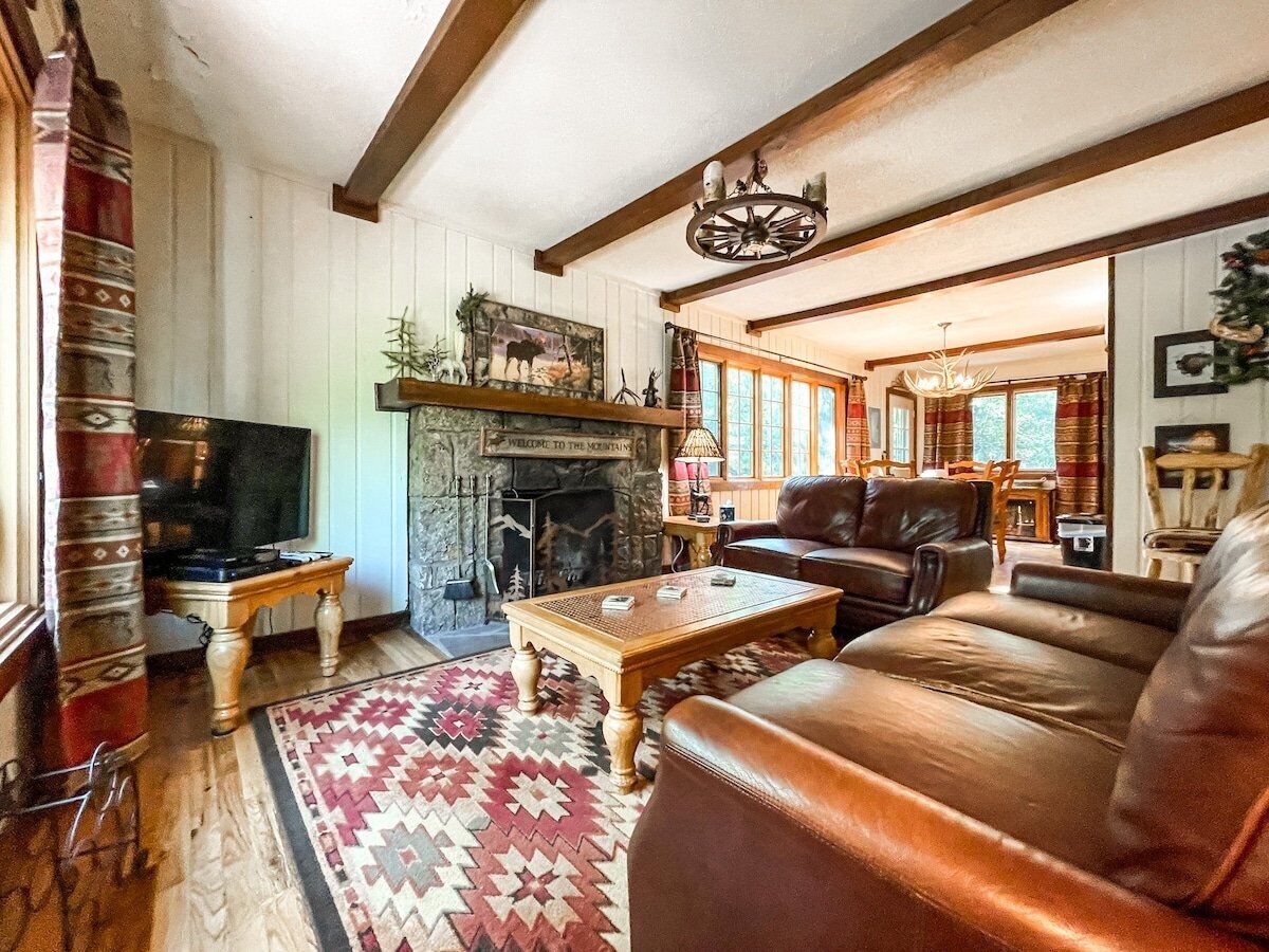 Una sala acogedora con chimenea, sofá de cuero y televisor.