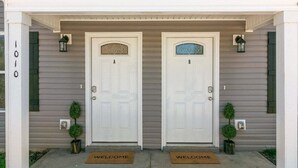Une entrée avec une double porte et un paillasson sur lequel est écrit « BIENVENUE ».
