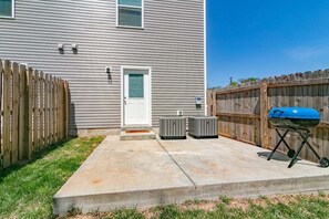 A residential backyard with a concrete patio, a wooden fence, a white door, and a blue grill. - Unit #A 1010 Franklin St (Clarksville)