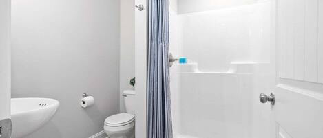 A bathroom with a shower, toilet, and sink.