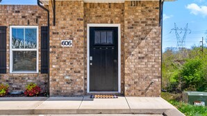 Un bâtiment en briques avec une porte noire et une plaque portant le numéro 606.