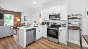 A modern kitchen with white cabinetry, a built-in oven, and a microwave. - The Spot 281 Liberty Pkwy (Clarksville)