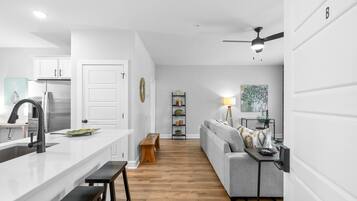 A modern kitchen with white cabinetry, a central island with a sink, and a dining area with a bench.