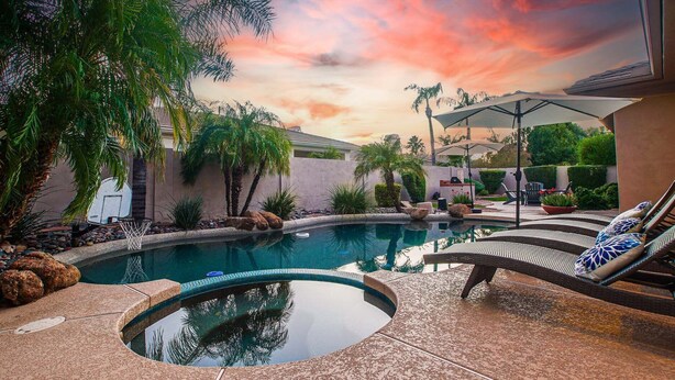 Piscina con hidromasaje, sillas de descanso y zona de patio con sombrillas.