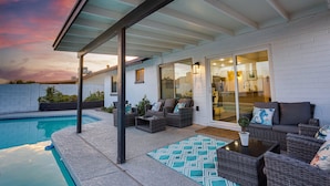 Portico esterno coperto con piscina, mobili in vimini e vista sull'interno della casa.