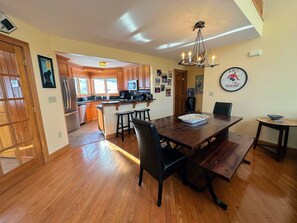A spacious kitchen with wooden cabinets, a central island, and a dining area with a large wooden table and chairs. - Cr14 (Bretton Woods)