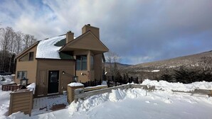 Un bâtiment à deux étages, dont le toit est recouvert de neige, et qui possède une terrasse en bois à l’avant.