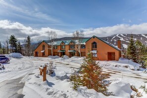 A multi-story building with a green roof, surrounded by snow-covered ground and trees. - Mwp35 (Bretton Woods)