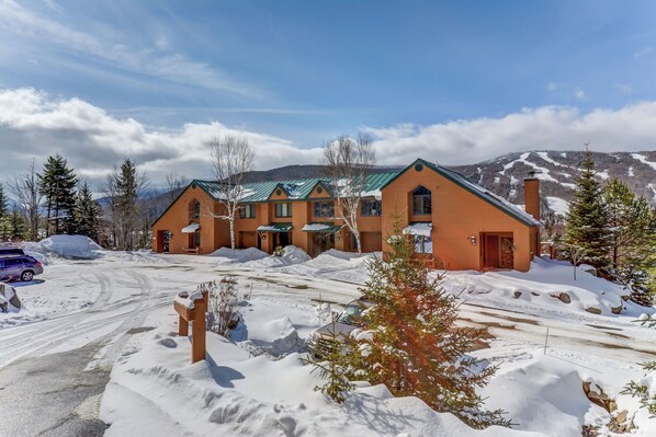 A large, two-story building with a green roof and multiple windows, surrounded by snow-covered ground and trees. - Mwp35 (Bretton Woods)
