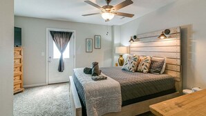 A bedroom with a bed, a ceiling fan, a bedside table, a lamp, and a window with curtains. - Unit #B 1010 Franklin St (Clarksville)