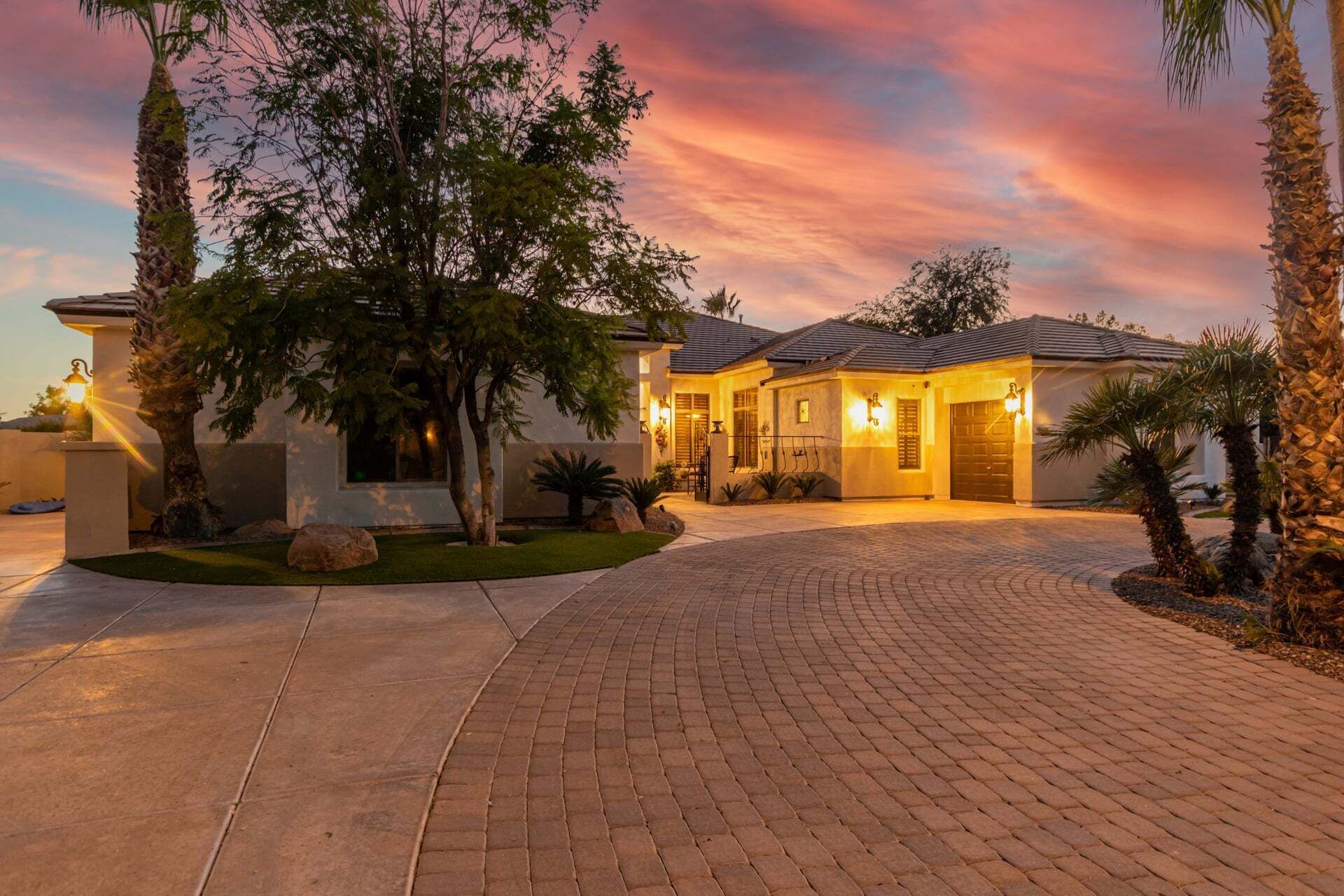 A residential property with a paved driveway, a well-maintained lawn, and a house with a tiled roof.