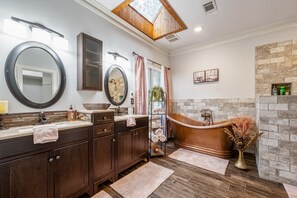 A modern bathroom with a large mirror, two sinks, a bathtub, and a stone accent wall. - Poolside Farm Serenity Group Perfect, Cozy Gazebo (Cartersville)