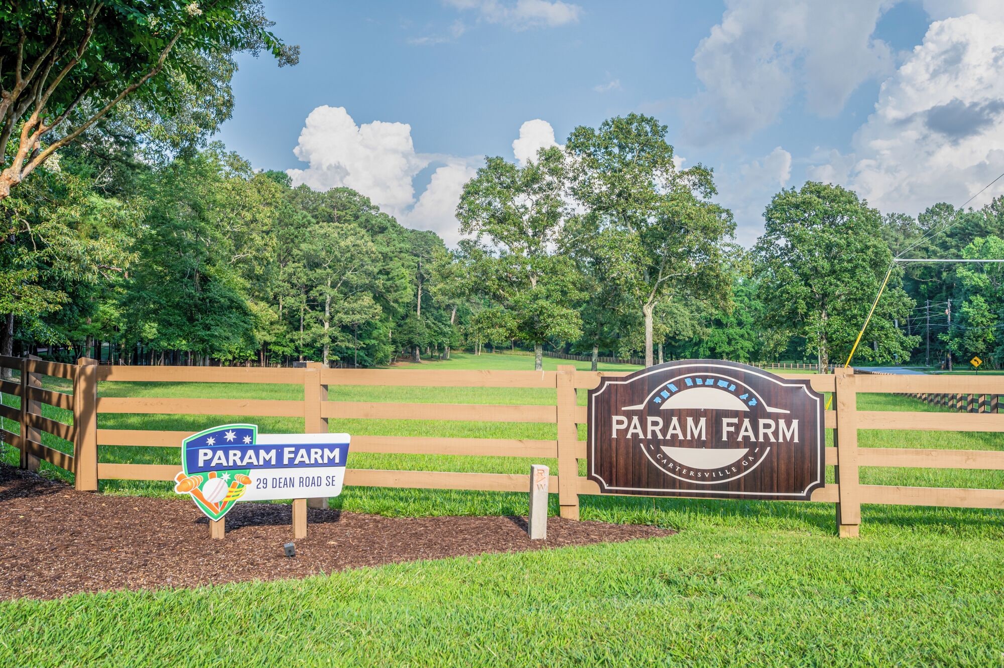 A farm entrance with a wooden fence and a sign indicating 'Param Farm' and '29 Dean Road SE'.
