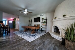 Una sala de estar con chimenea, una mesa de comedor y un televisor montado en la pared.