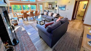 A spacious living area with a large gray sofa, wooden dining table, and chairs. There are multiple windows providing natural light and views of the outdoors. - Mwp29 (Bretton Woods)