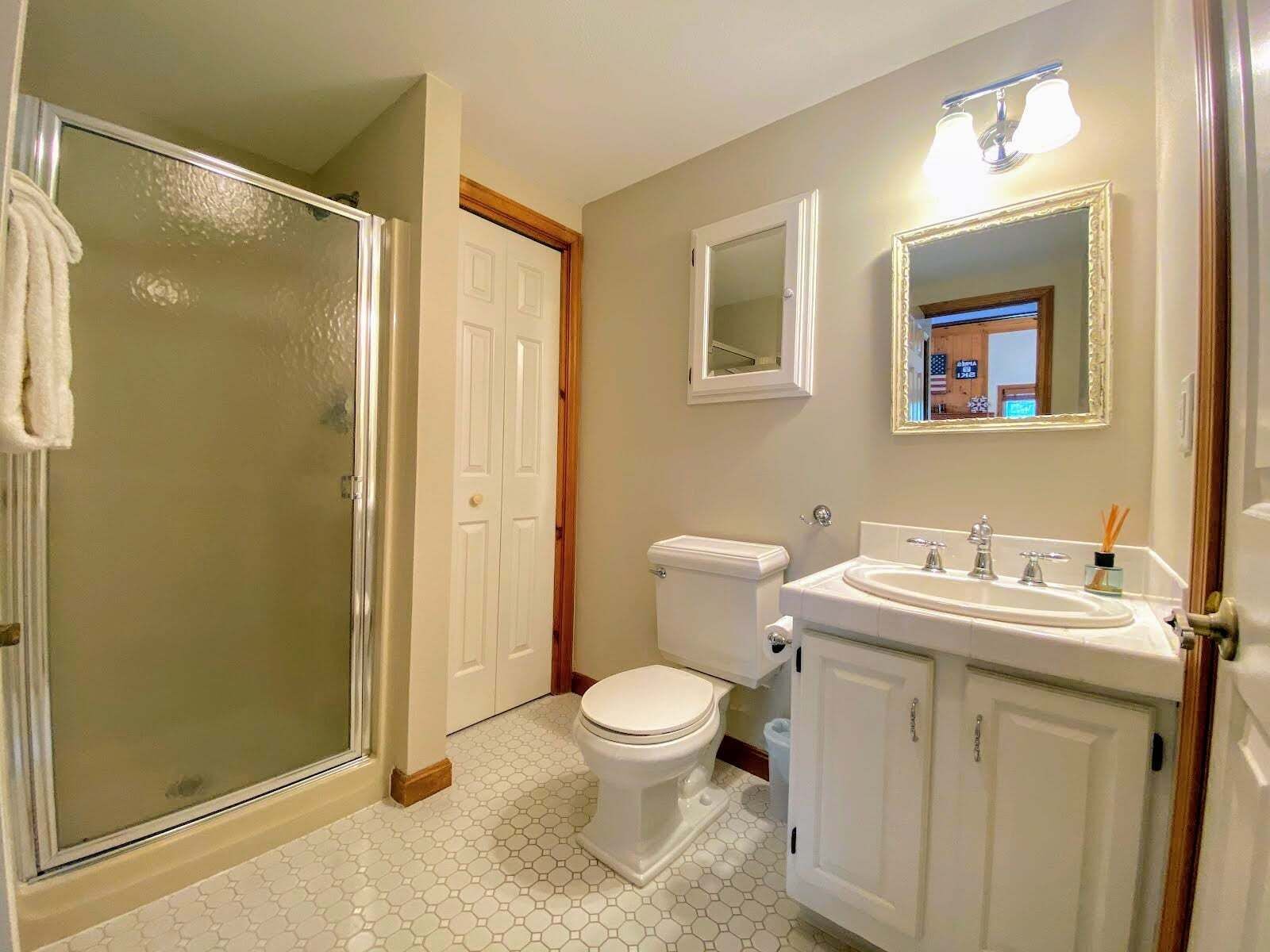 Un baño con ducha, inodoro, lavamanos y espejo.