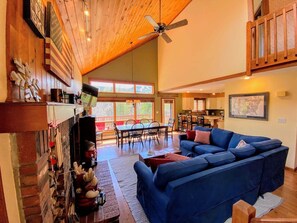 A spacious living area with a blue sofa, wooden ceiling, and a dining area with a table and chairs. - Mwp62 (Bretton Woods)