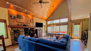 A cozy living room with a fireplace, a large sectional sofa, and a dining area with a table and chairs. - Mwp62 (Bretton Woods)