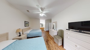 A hotel room with two beds, a television, a dresser, and a ceiling fan. - Club Villas Unit 23A - Lower Level (Sunset Beach)