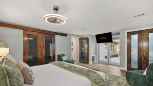 Ein modernes Hotelzimmer mit einem großen Bett, einem Fernseher und einer Schiebetür zu einem Balkon.