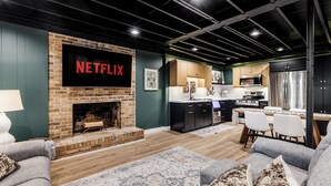 A modern living room with a fireplace, a kitchen area, and a dining space. - Lakefront + Kayaks + Dock + Screened in Porch | Home Sweet Bowen (Inman)