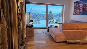 A modern living room with a large window, a sofa, a coffee table, and a painting on the wall. - Penthouse "Pfänderblick" Alpine panorama on Lake Constance near Lindau (Sigmarszell)