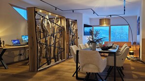 A modern dining area with a wooden partition, a dining table with chairs, and a view of the outdoors through large windows. - Penthouse "Pfänderblick" Alpine panorama on Lake Constance near Lindau (Sigmarszell)