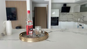 Une cuisine moderne avec un plan de travail en marbre, une bouteille de Tom Tom Saint James et un plateau contenant des bocaux en verre.