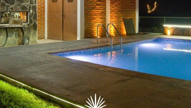 Ein zweistöckiges Gebäude mit Swimmingpool, Stein- und Backsteinmauern und einem Balkon mit Geländer.