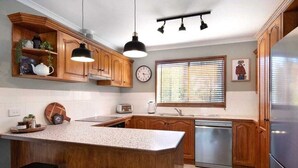 A kitchen with wooden cabinets, a central island, a built-in dishwasher, and a refrigerator.