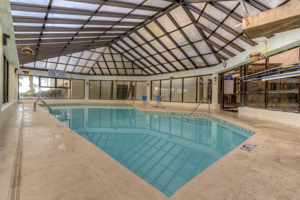 An indoor swimming pool with a glass ceiling, clear pool area, and a sign indicating no diving.