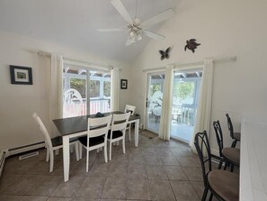 A dining area with a table and chairs, a ceiling fan, and a view through glass doors. - Pool. Close to Beach. Sleeps 11 Guests (Villas)