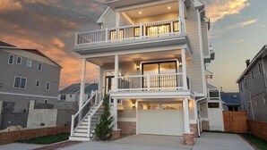 Un edificio residenziale su due piani con un balcone al piano superiore, un garage e una scala che conduce all'ingresso.