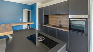 Una cucina moderna con mobili scuri, un piano di lavoro in legno e un forno integrato.