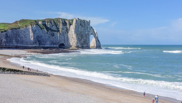 Paesaggio costiero con una scogliera imponente e una spiaggia.
