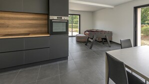 Una cucina moderna con mobili scuri, un piano di lavoro in legno e un forno a incasso.