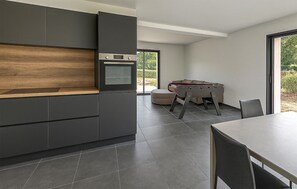 A modern kitchen with dark cabinetry, a wooden countertop, and a built-in oven. - Maison Campagne Normandie (Elbeuf-sur-Andelle)