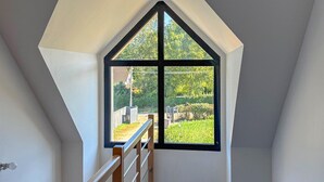 Una stanza con soffitto spiovente e una grande finestra con cornice nera.