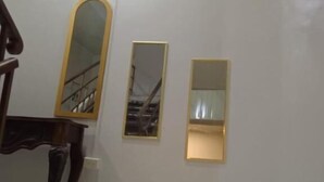 Una stanza con un pianoforte, un grande specchio e due specchi più piccoli appesi al muro.