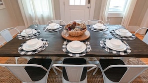 A dining table set for six with checkered placemats, white plates, and glasses. - The Bulldog Farmhouse - 100+ Year old Home (Athens)